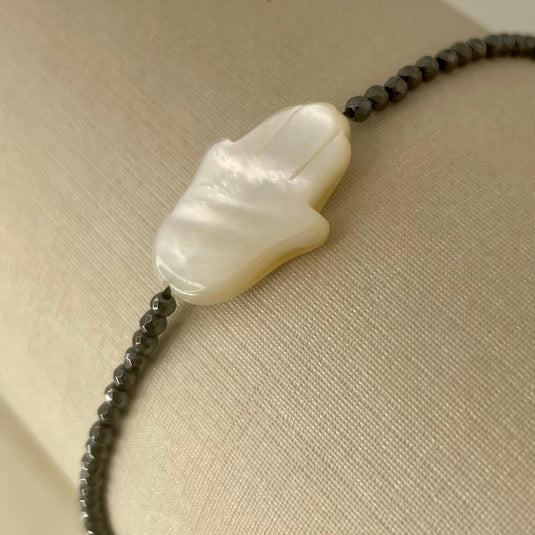 Pulseira de Hematita com Mão de Fátima em Madrepérola e Liga de Silicone – Proteção e Estilo em Cada Detalhe