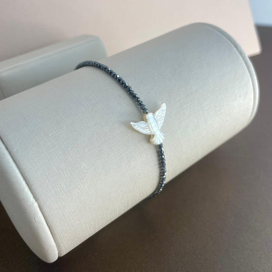 Pulseira de Hematita com Divino Espírito Santo em Madrepérola e Liga de Silicone – Proteção e Estilo em Harmonia.